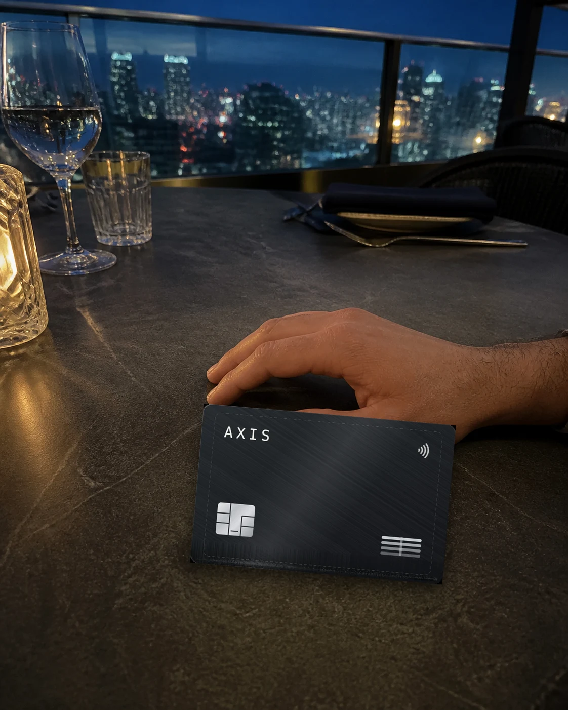 The AXIS card on a rooftop table, the city lit behind it